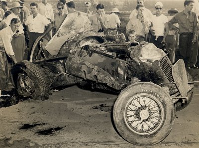 The remains of George Robson's car.  The same old Lou Moore car Floyd Roberts drove to victory at Indy in 1938 and died driving in 1939.  Later, tne new car owner, and former driver Cliff Bergere took the car back tohis shop and chopped it to pieces.  The car was sponsored by Burd Piston Rings in 1938 and Noc-Out Hose Clamps when Robson drove it in 1946.  In the upper left corner you can vaguely see the Lakewood Grandstands.  Photo courtesy Eddie Samples